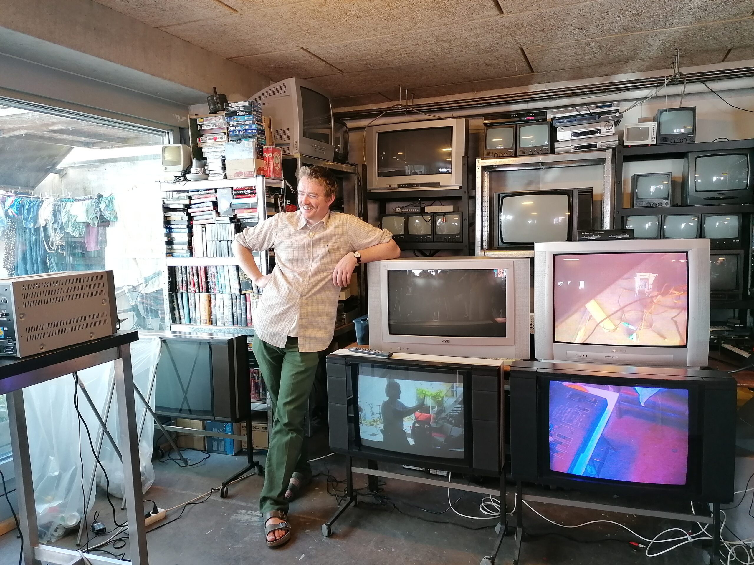 Liam standing next to a bunch of tvs